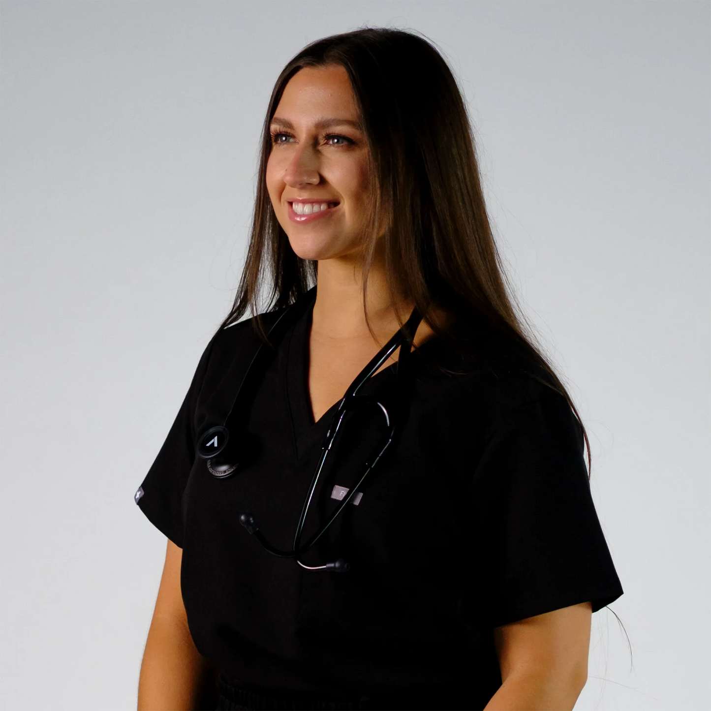 Model smiling posing with a black cardiology stethoscope