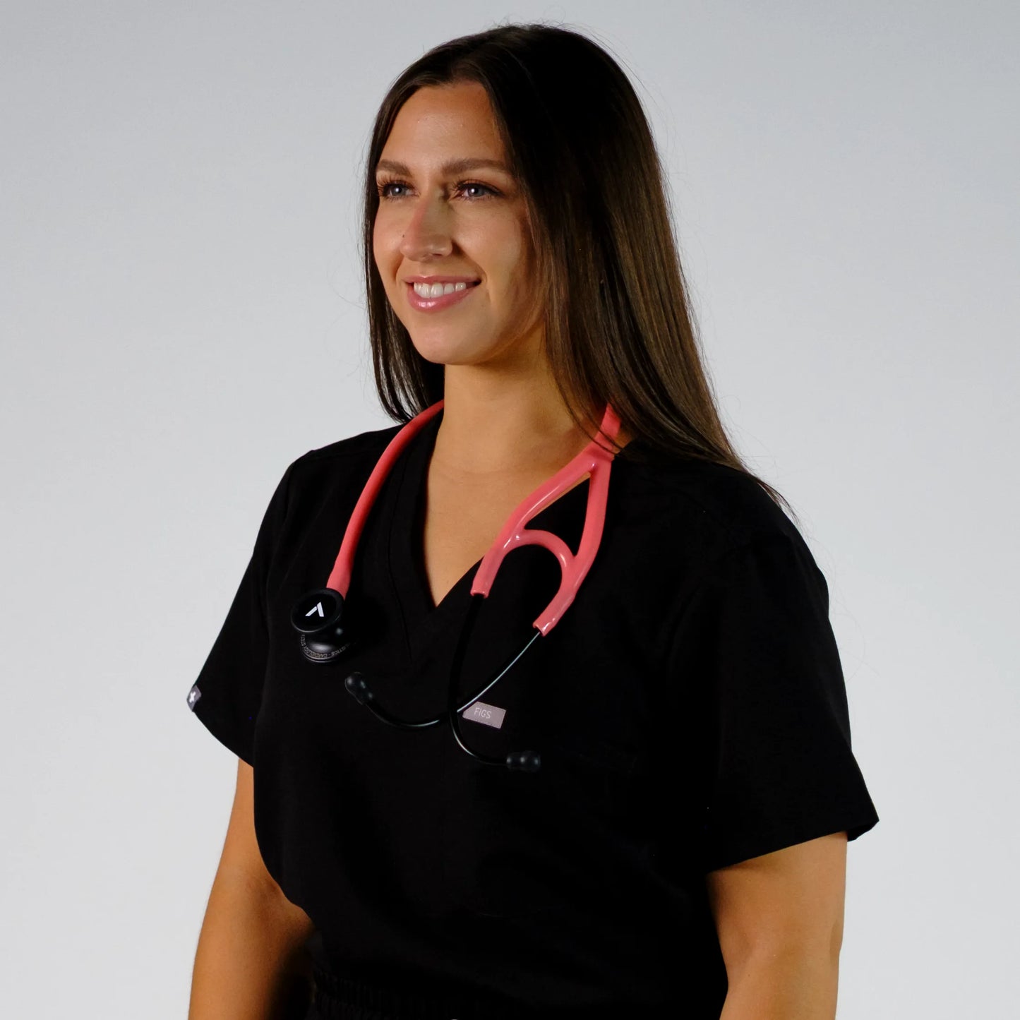 model smiling with a coral cardiology stethoscope