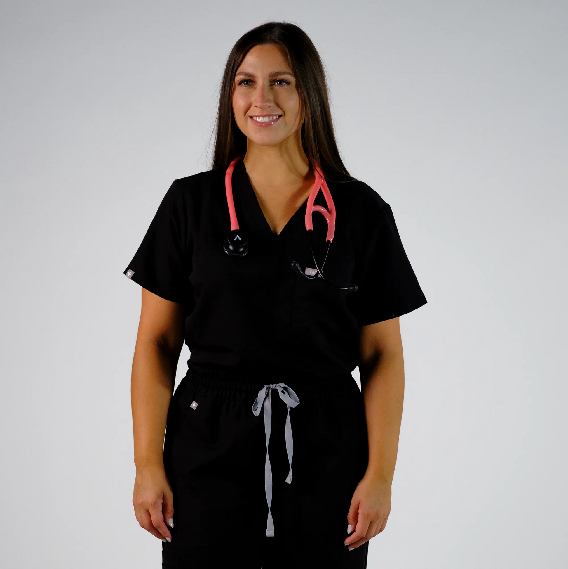 model smiling with coral cardiology stethoscope