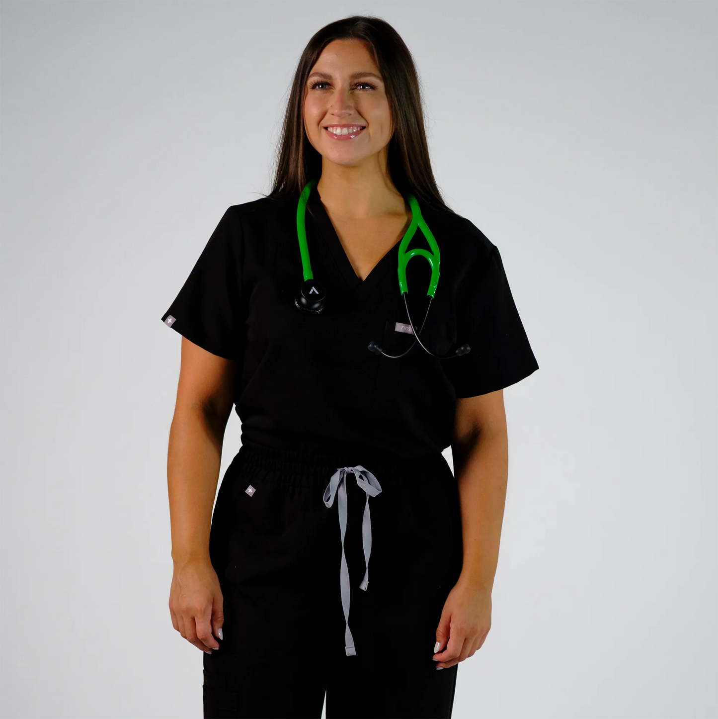  model smiling with a green cardiology stethoscope