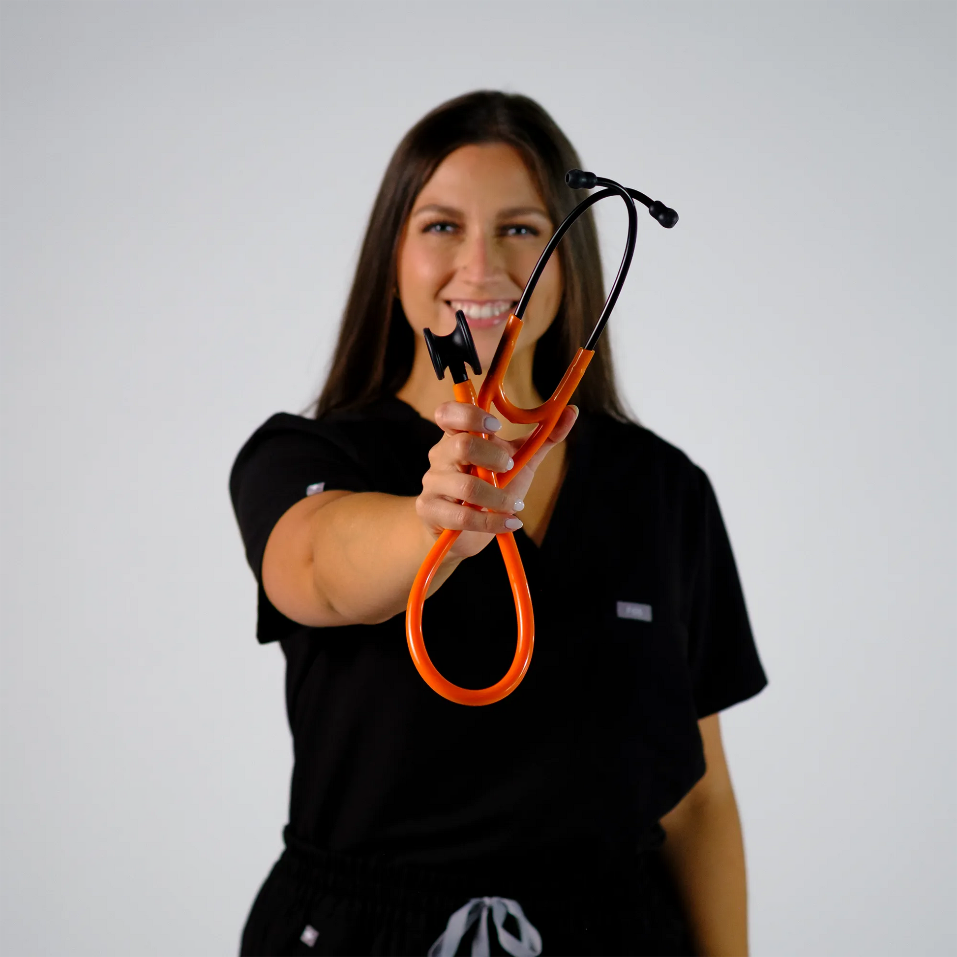 model smiling with orange cardiology stethoscope