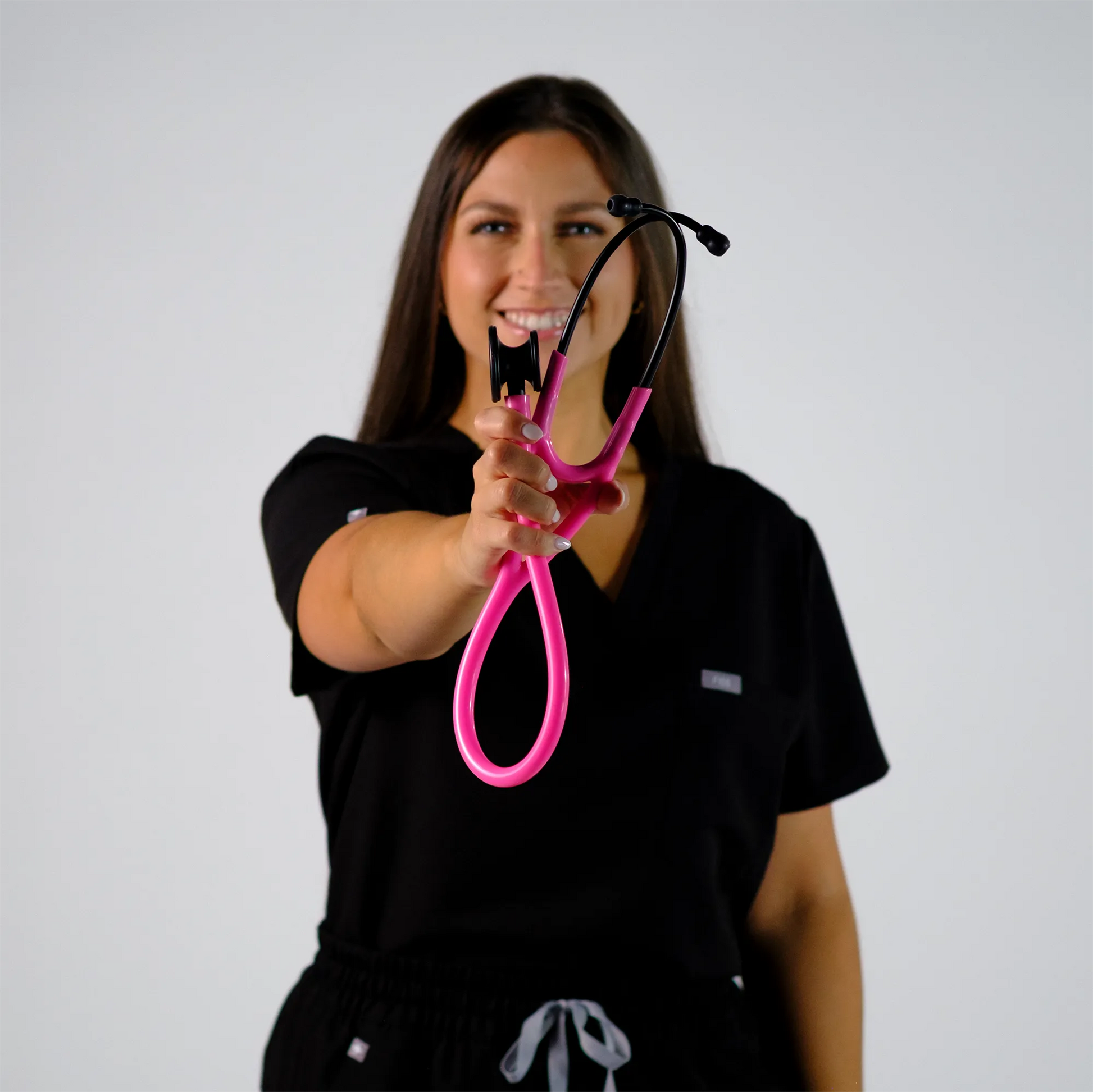 a model smiling with  a pink cardiology stethoscope