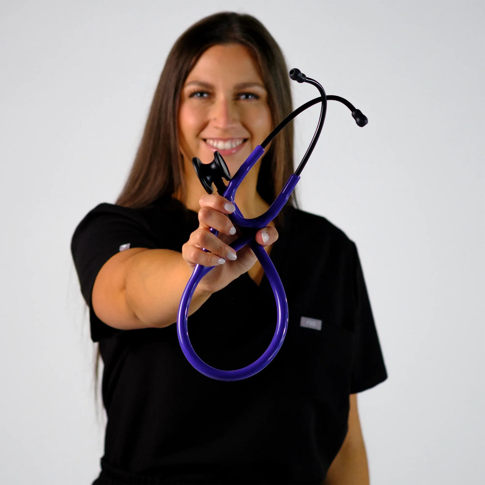 model smiling with a purple cardiology stethoscope