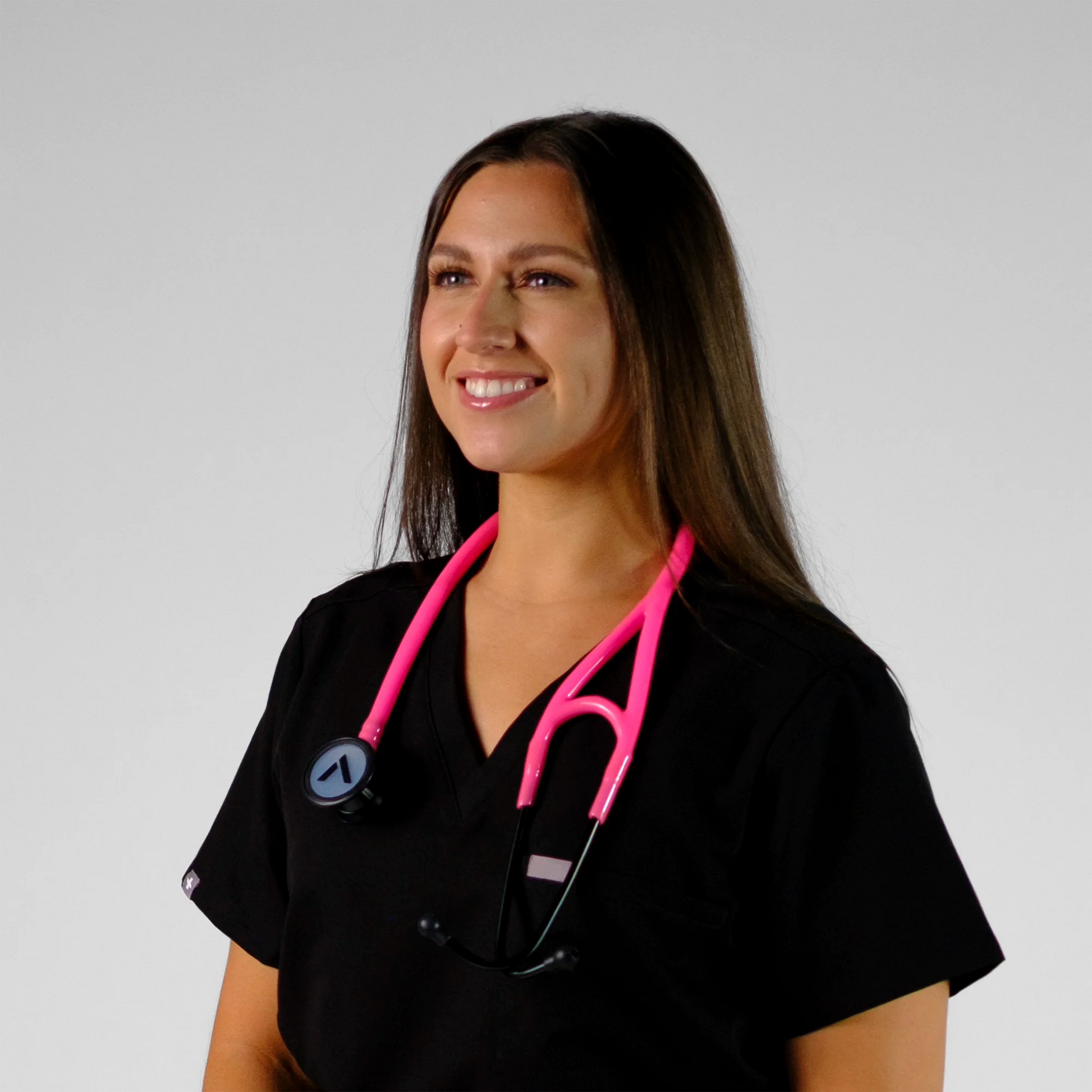model smiling wearing a pink cardiology stethoscope