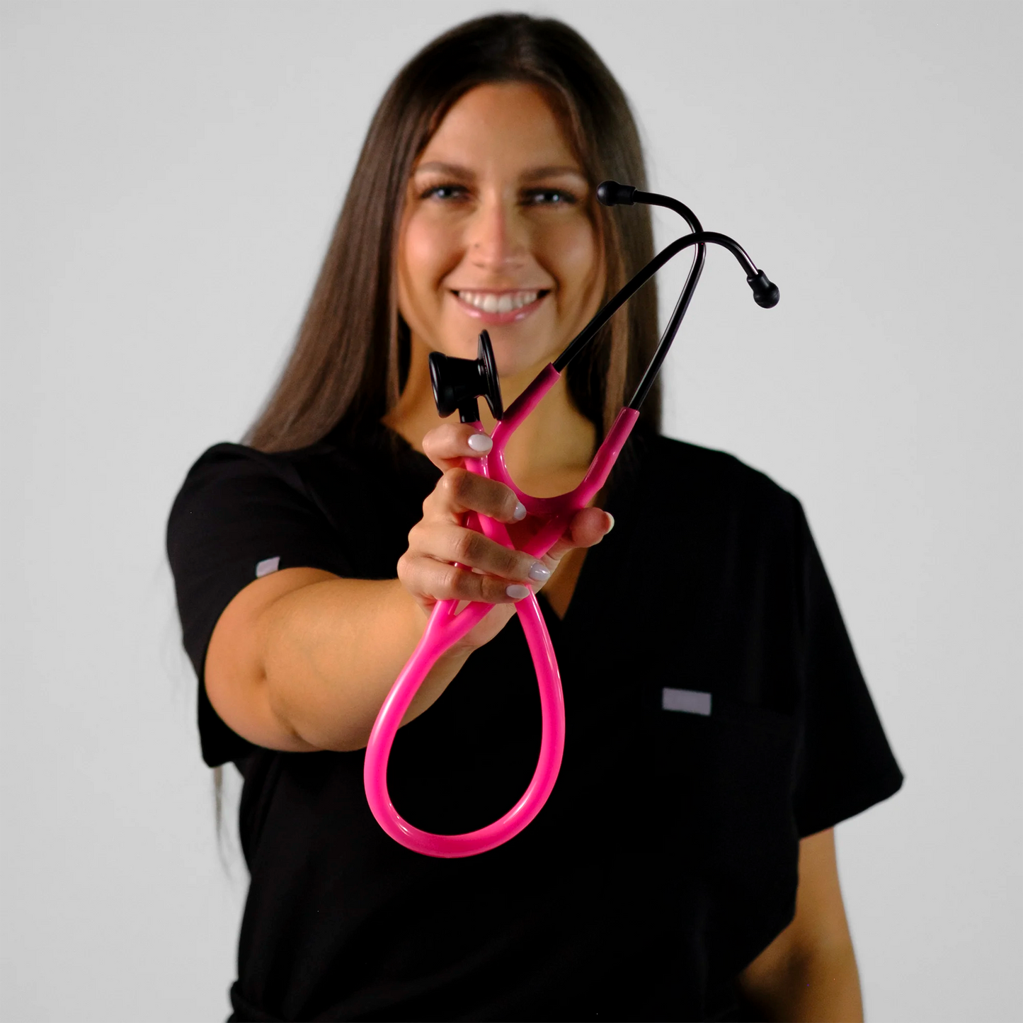 model holding a pink cardiology stethoscope