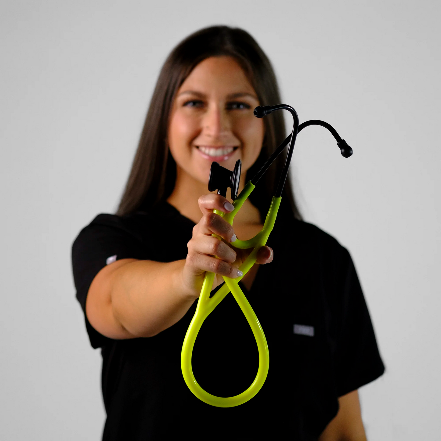 model holding a neon yellow cardiology stethoscope