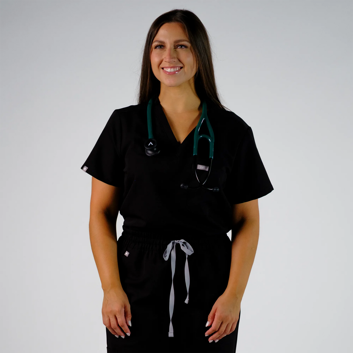 a model smiling with a teal cardiology stethoscope
